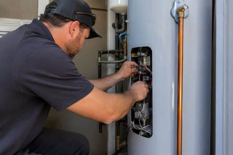 Plumber repairing a residential gas water heater during service in Boerne, TX.